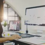 Graphic designer working on computer using digital tablet at office.
