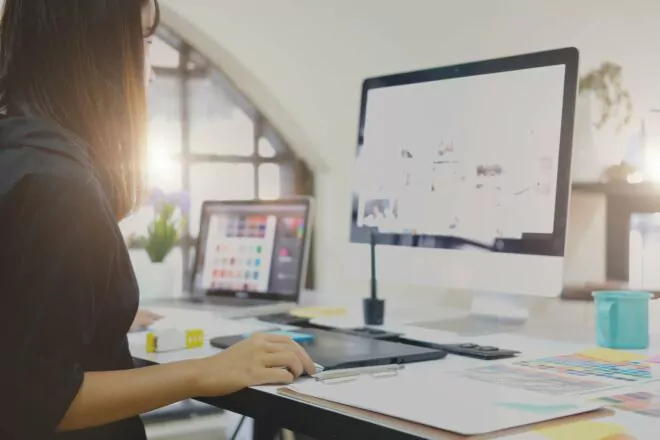 Graphic designer working on computer using digital tablet at office.